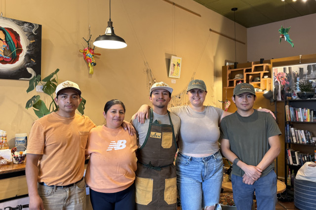 Three men and two women standing shoulder to shoulder in a group photo of staff at a coffee shop.