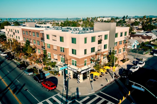 Aerial view of a beige corner building, with a coffee shop on the street level.