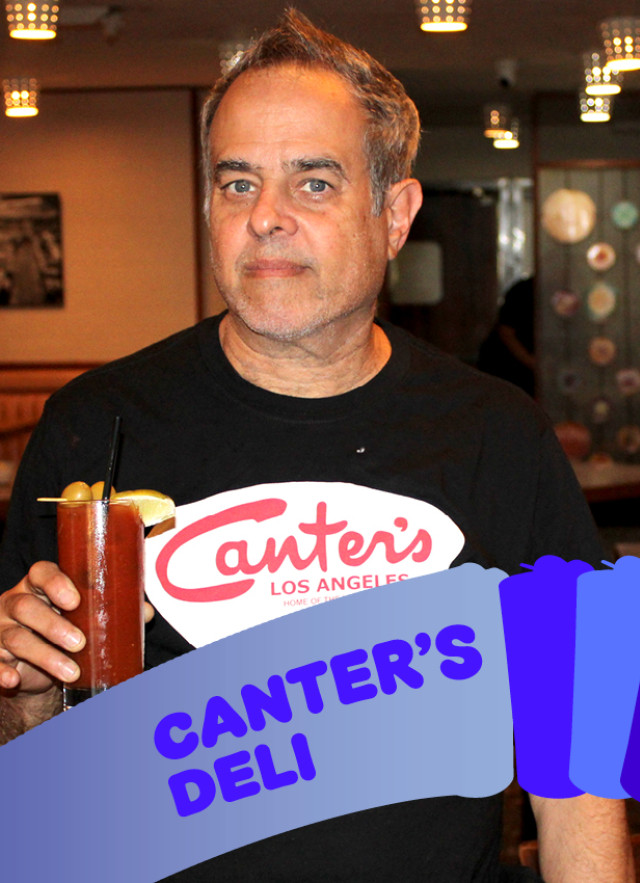 man holding cup wearing black t shirt with white and red graphics. 