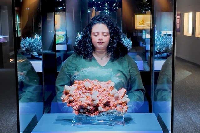 Visitor in green shirt looking into a glass case with an orange cauliflower-shaped specimen inside