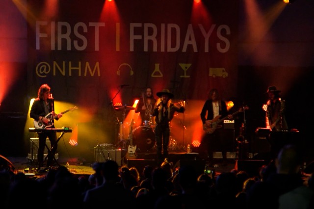 Band playing on stage under red and yellow lighting