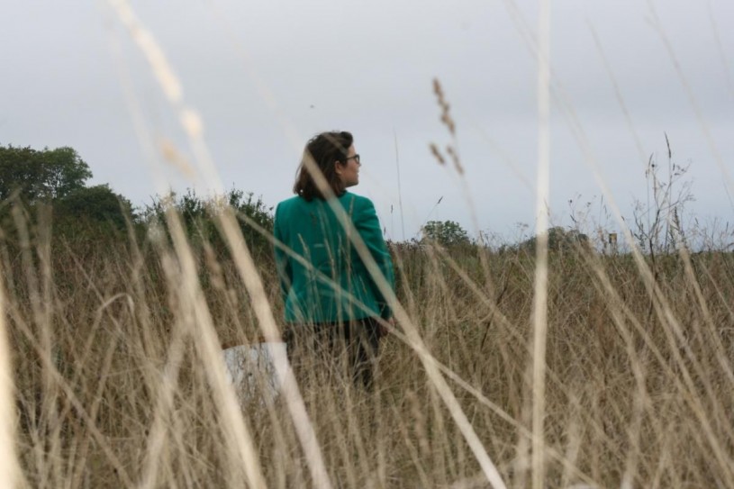 Emily Hartop stands in tall grass holding a butterfly net