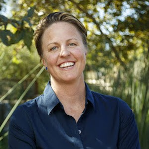 Scientist smiles at camera with greenery behind her
